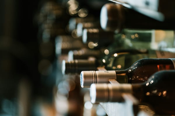 Wine bottles resting on a wooden rack in a retailer's cellar
