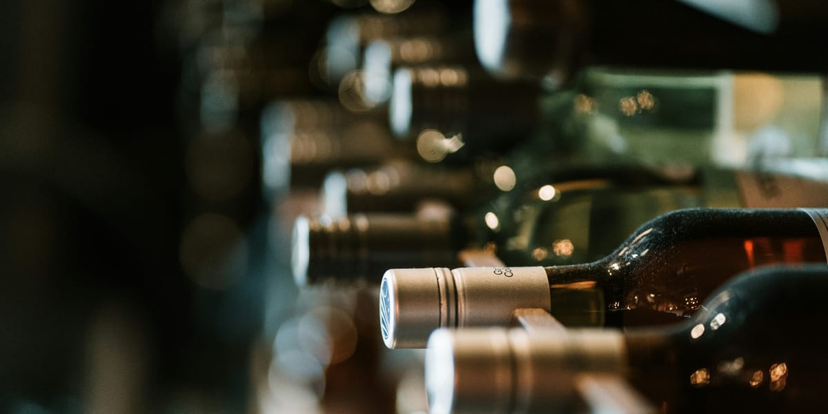 Wine bottles resting on a wooden rack in a retailer's cellar